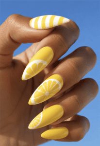 Bright yellow lemon almond nails with citrus slice nail art, white striped accents and glossy summer fruit manicure