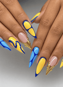 Blue and yellow abstract stiletto nails with geometric color blocking, gold chrome accents and glossy modern nail art on a nude base