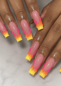 Neon pink and yellow flame French tip coffin nails with glossy nude base, fiery ombré nail art and bold summer manicure