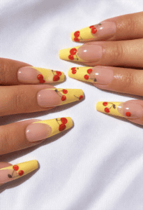 Pastel yellow French tip almond nails with cherry nail art, glossy nude base and cute fruit-inspired summer manicure