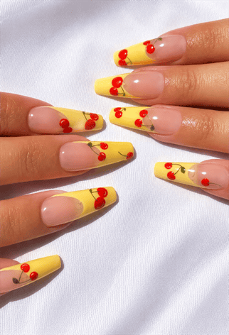Pastel yellow French tip almond nails with cherry nail art, glossy nude base and cute fruit-inspired summer manicure
