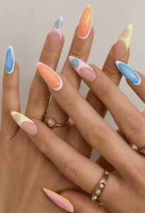 Pastel abstract French tip almond nails with peach, blue, lavender and butter yellow color block nail art on a glossy nude base