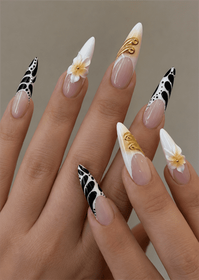 Black, white and gold luxury stiletto nails with abstract French tips, 3D floral accents and metallic embellishments on a glossy nude base
