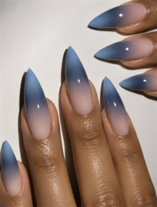 Dusty blue ombré stiletto nails with a glossy nude fade, soft gradient finish and elegant minimalist manicure