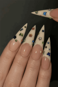 Milky white French tip stiletto nails with colorful rhinestone charms, 3D gem embellishments and elegant luxury nail art