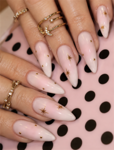 Soft pink ombré almond nails with gold celestial star nail art, minimalist gold studs and elegant glossy manicure