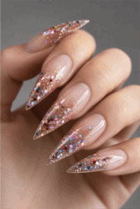Rose gold glitter ombré stiletto nails with chunky holographic glitter, glossy nude base and sparkling luxury manicure