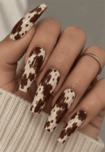 Brown and cream cow print coffin nails with irregular animal print spots and a glossy finish