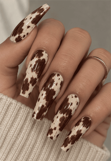 Brown and cream cow print coffin nails with irregular animal print spots and a glossy finish