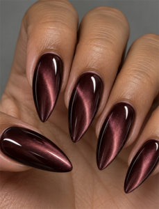 Long burgundy stiletto nails with dimensional cat eye shimmer and a glossy high-shine finish