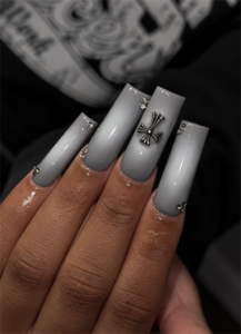 Gray ombré coffin nails with silver cross charm, rhinestone accents and a glossy finish