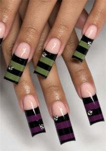 Extra-long square Halloween nails with black, olive green and purple stripes, nude bases, and rhinestones.
