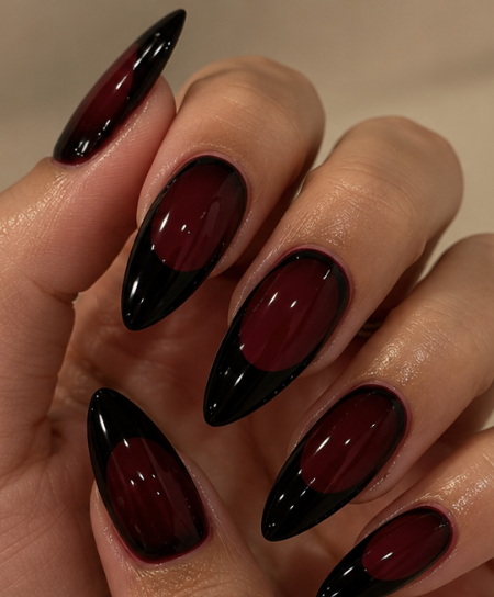 Long almond nails featuring glossy burgundy bases and sharply curved black French tips.