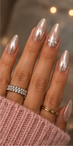 Champagne chrome almond nails with pearlescent metallic shine and delicate white snowflake accent designs.