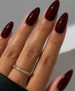 Long almond nails painted deep burgundy wine red with a smooth, glossy finish.