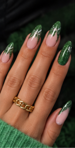 Almond nails with sheer pink bases, emerald green glitter French tips and sparkling green accent nails.