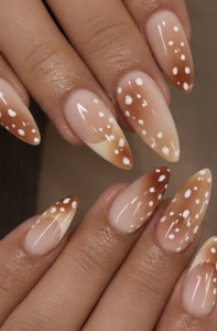Long almond nails with nude-to-caramel ombré, chocolate accents, scattered white polka dots and glossy finish.