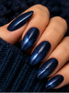 Long almond nails coated in deep midnight navy polish with fine blue shimmer and glossy shine.
