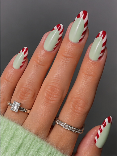 Long almond nails with pastel mint green polish and red-and-white striped candy cane French tips.