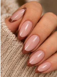 Long almond nails featuring warm mocha brown French tips over glossy sheer pink-nude polish.