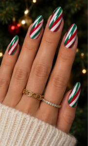 Long almond nails with glossy white polish and alternating red and green diagonal Christmas stripes.