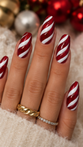 Long square nails with glossy red polish and flowing white diagonal candy cane swirl stripes.