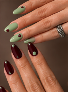 Medium almond nails in matte sage green and burgundy with contrasting single-dot accents.