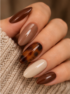 Long almond nails in glossy chocolate, taupe, cream and amber tortoiseshell with mixed neutral finishes.